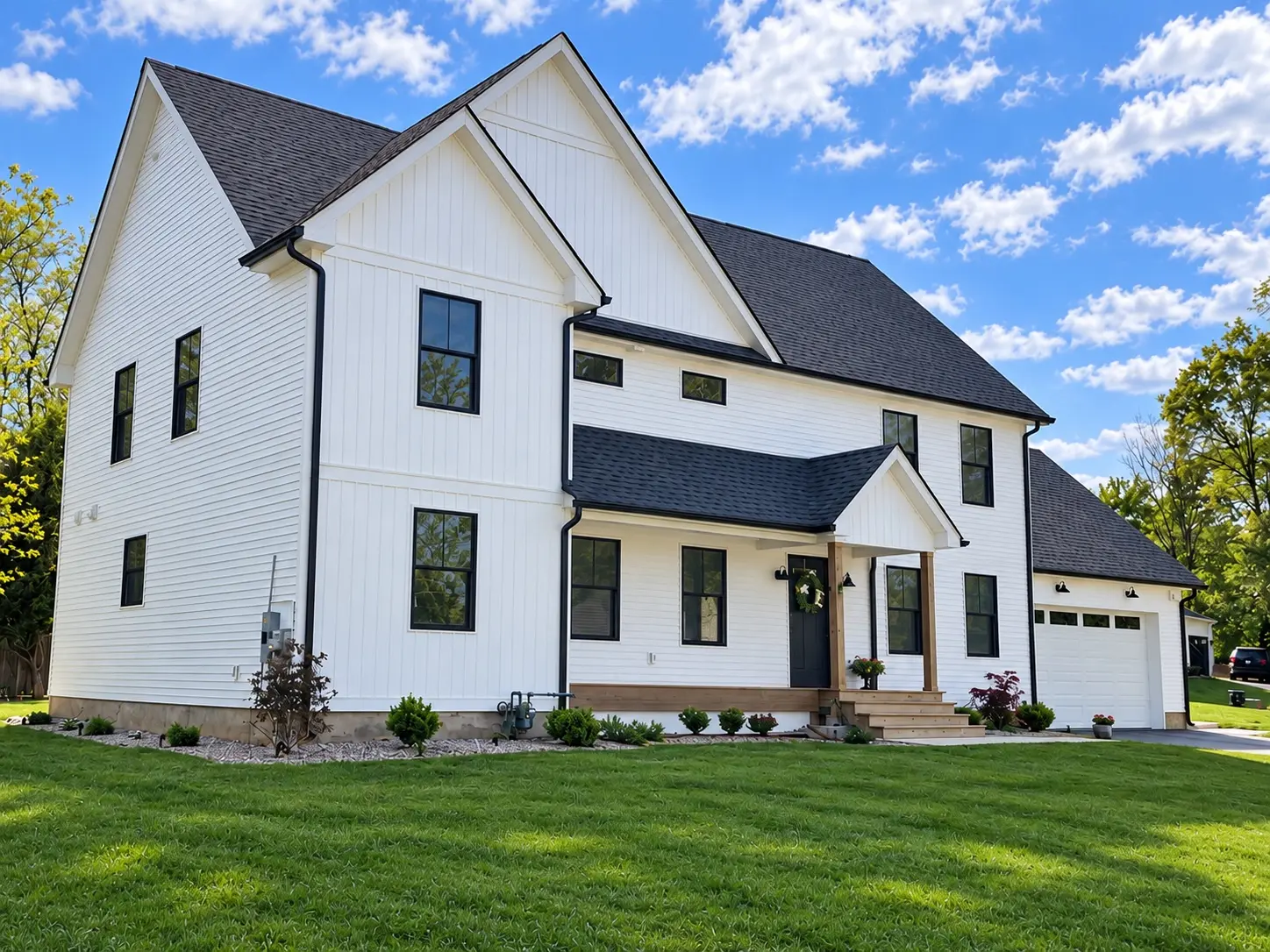 Completed new-construction white home with black windows and landscaped lawn