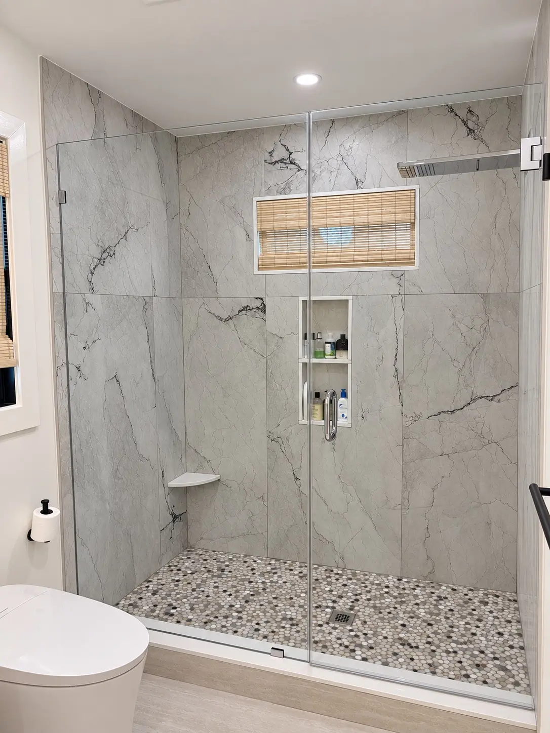 Completed marble-look walk-in shower with frameless glass enclosure