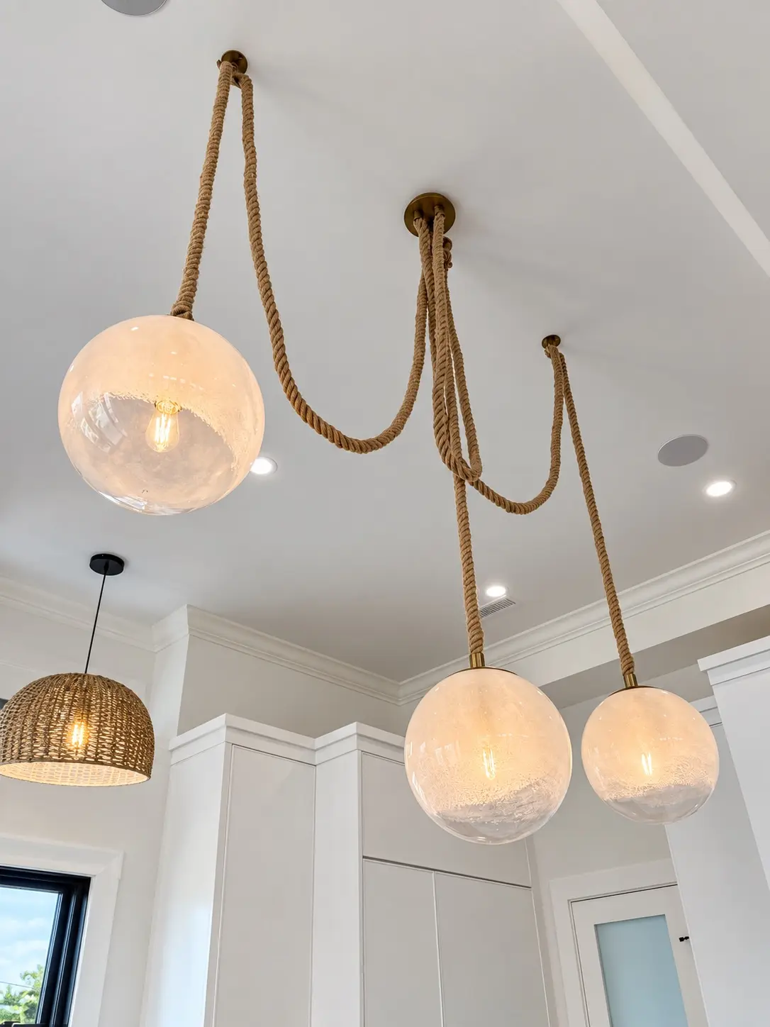Decorative rope-hung pendant lights installed over a kitchen island
